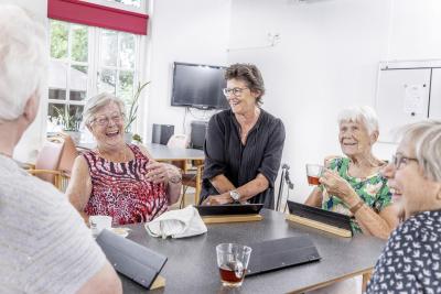 Senioren spelen Rummikub, je ziet een lachende vrouw