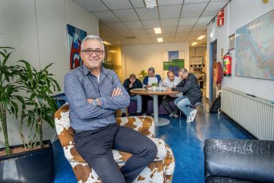 Medewerker kijkt in camera met op de achtergrond een groep inwoners